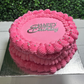 Pink vintage style birthday cake with 'Happy Birthday' text on a green outdoor background