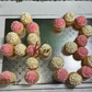Cupcakes arranged to form the number '25' with pink and white frosting on a metallic surface.